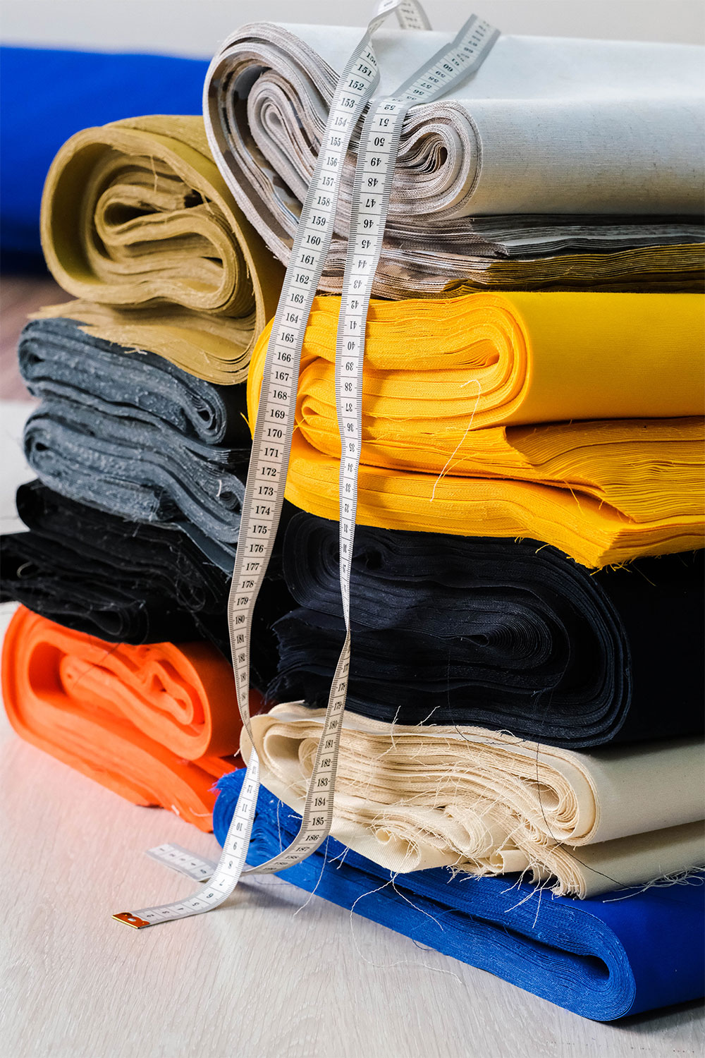 Stapel bunter Naturstoffe auf einem Tisch im Peter Kastenholz Stoffladen und Outlet – vielfältige Farben und Materialien für nachhaltige Näh- und Wohnprojekte
